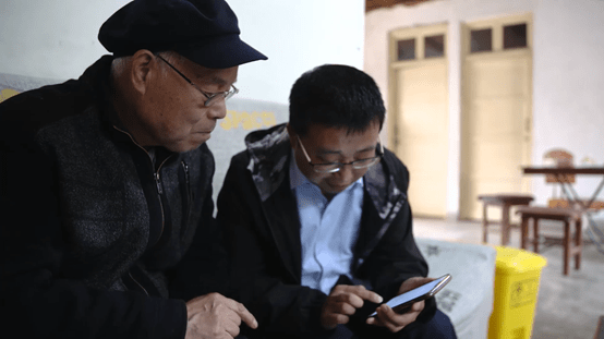 ▲ 在陜西西安，美團優(yōu)選社區(qū)電商服務(wù)站站長正教老人使用手機下單。建偉?攝